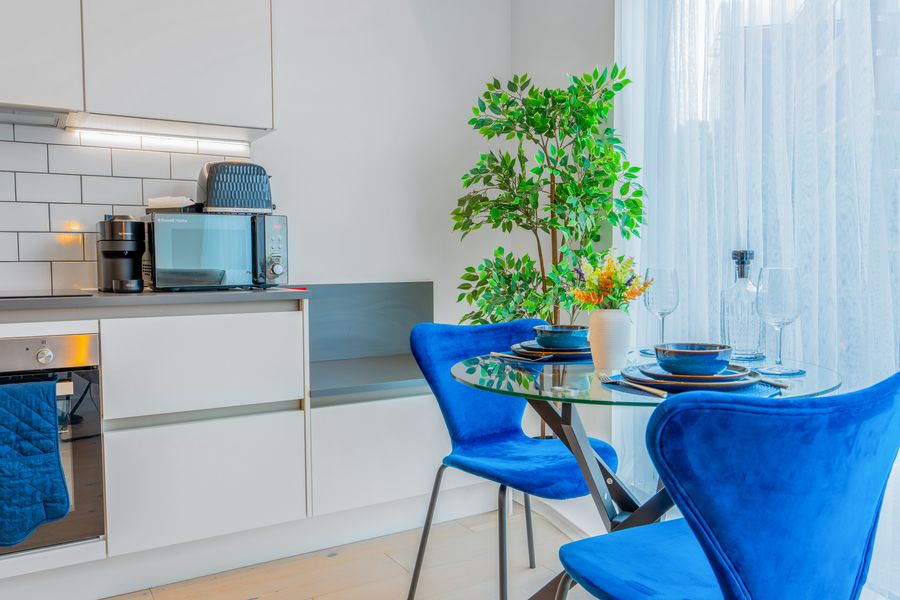 Kitchen and dining area with blue chairs and a plant