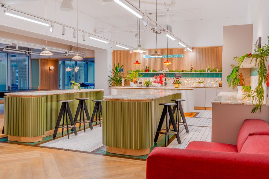 Shared lounge with a red sofa, green kitchen islands and stools