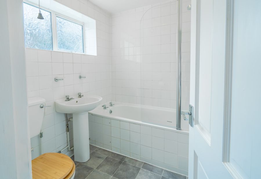 Bathroom with white tiles, a bath and a pedestal basin