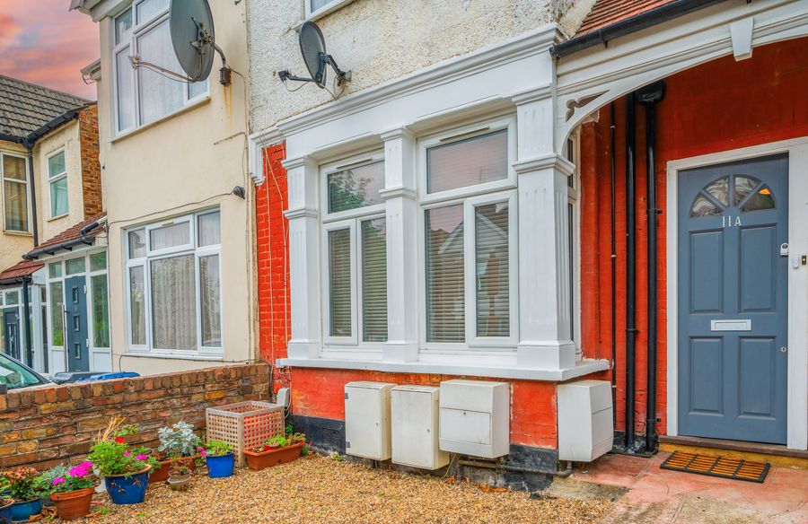 Front of a terraced house with a grey door and flower pots