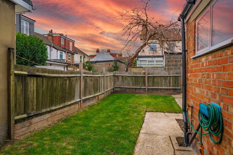 Rear garden with a lawn and wooden fence at sunset