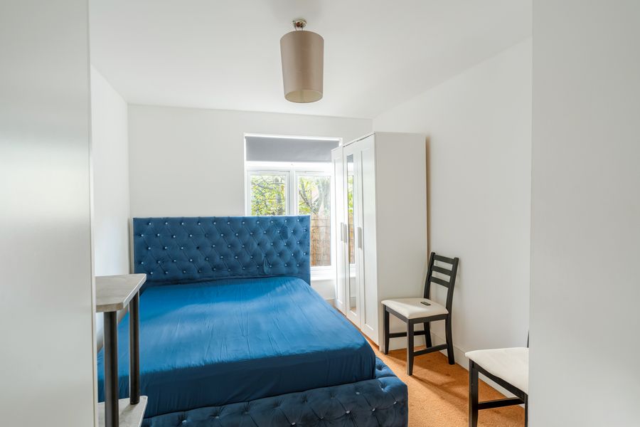 Bedroom with a blue upholstered bed and a window