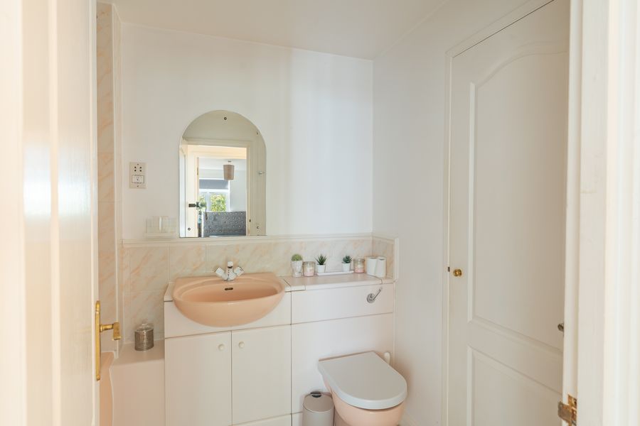 Bathroom with a peach basin and an arched mirror
