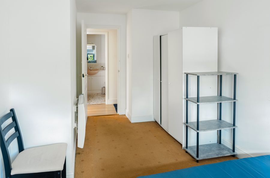 Bedroom with shelves, a chair and a fitted wardrobe