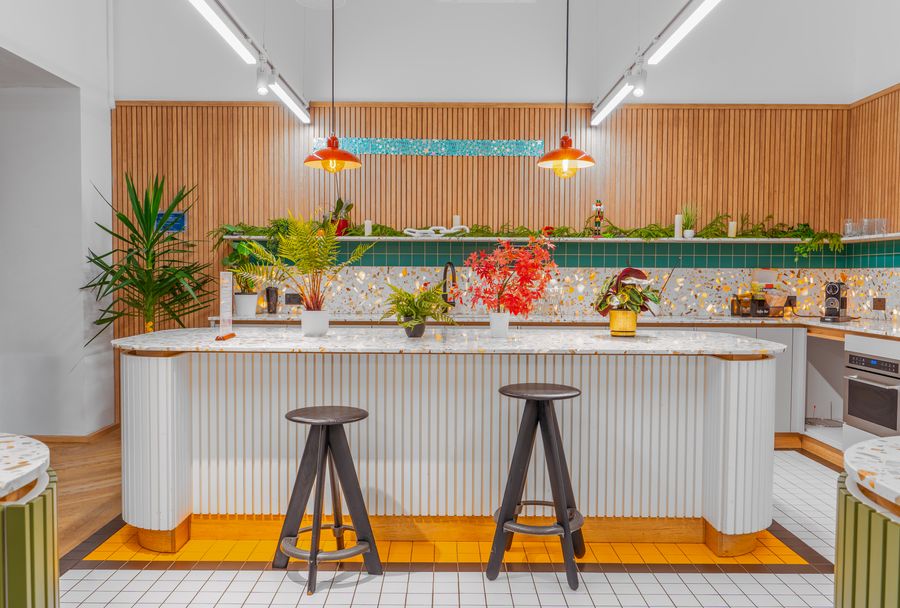 Kitchen with wooden slatted walls, a terrazzo island and two stools